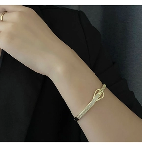 Gros plan d'un bracelet doré à boucle de ceinture serti de cristaux de zircone brillants