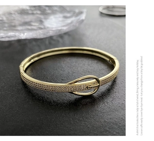 Détail du bracelet boucle de ceinture doré serti de zircons sur fond sombre