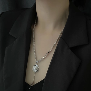 Élégant collier à pendentif perle argentée avec gland long sur un blazer noir