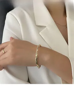 Close-up of elegant gold plated zircon open bracelet worn with white suit sleeve