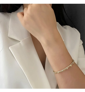 Close-up of gold double-layer bracelet with white zircons and small heart charms on wrist