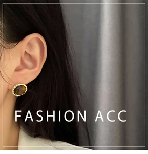 Close-up of vintage tiger eye stud earring with gold twisted rope border on ear
