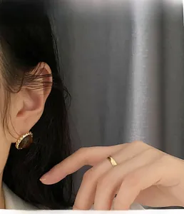 Close-up of vintage gold twist earrings with brown tiger eye stone on model