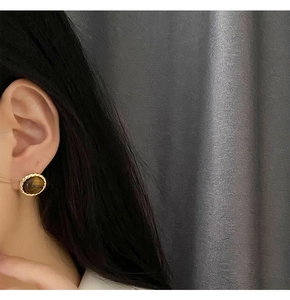 Detailed view of vintage tiger eye stud earrings with twisted gold edge on ear