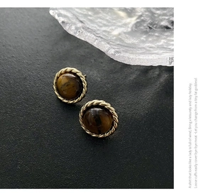 Detailed close-up of vintage tiger eye stud earrings with twisted gold rope border
