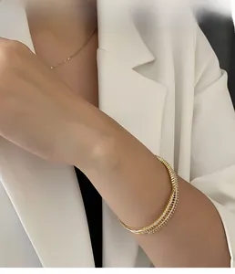 Close-up of a layered gold zircon bangle worn by a model in elegant white attire