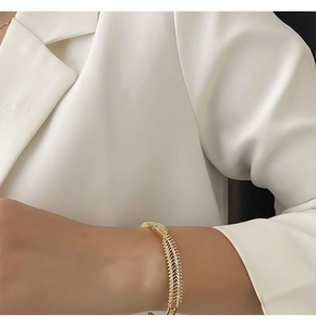 Close-up of a luxury gold-tone cross bracelet with pavé-set zircon on a woman's wrist