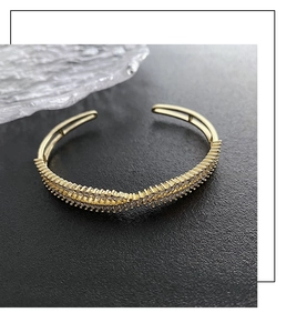 Detailed view of luxury gold crisscross bangle with micro-paved sparkling zircon stones