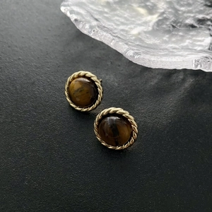 Vintage gold rope frame tiger eye stone earrings on a premium black leather surface