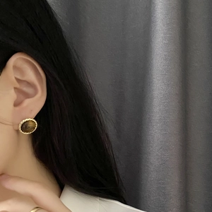 Vintage gold rope frame tiger eye stone stud earrings worn by a model in close-up