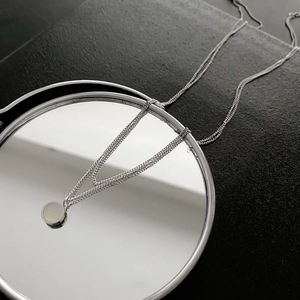 Detailed view of silver titanium steel necklace with white shell pendant on mirror