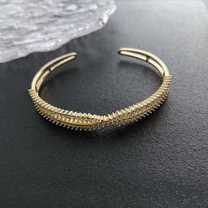 Elegant gold-tone crisscross open cuff bracelet with pavé cubic zirconia on black stone