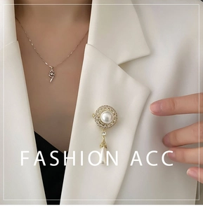 Detailansicht von Tropfenperlen-Brosche und Knoten-Halskette an einem weißen Blazer