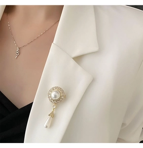 Detail der eleganten Tropfenperlen-Brosche mit Vintage-Kristall-Sonnenblume auf weißem Anzug