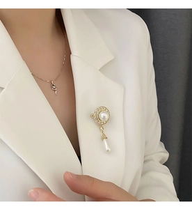Elegante goldene Perlenbrosche mit runden und tropfenförmigen Perlen auf weißem Blazer
