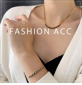 Detail of gold snake chain necklace and bracelet set with green zircon stones on a model