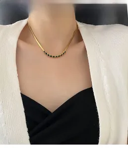 Model wearing gold snake chain necklace with curved emerald green zircon pendant jewelry