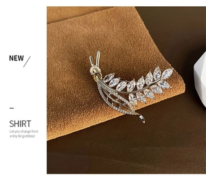 Macro detail of elegant gold wheat brooch with marquise-cut zircon stones on brown fabric