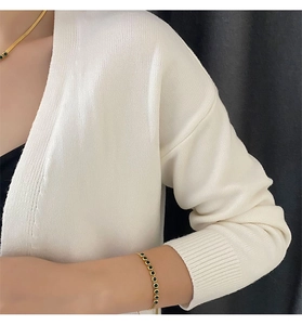 Detailed view of elegant gold necklace and bracelet set with round green gemstones on model