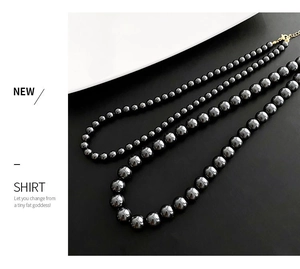 Détail de colliers de perles noires superposés en trois tailles avec fermoirs dorés