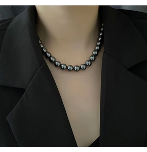 Gros plan d'un collier de perles sombres lustrées sur mannequin en costume élégant