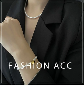 Detail view of pearl necklace and bracelet with gold accents on a black blazer model