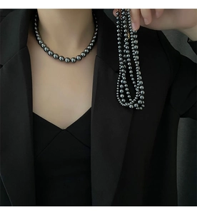 Gros plan d'un collier de perles gris foncé et d'un bracelet multi-rangs assorti