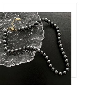 Détail macro du collier de perles noires avec fermoir en or K18 et chaîne de rallonge