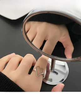 Détail de la bague coeur argentée ajourée portée par un mannequin avec reflet sur miroir