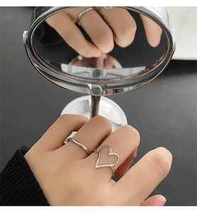 Vue détaillée du miroir d'un ensemble de bagues cœur en argent sur une main, style minimal