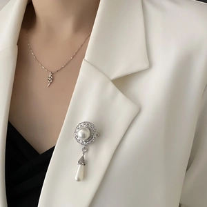 Elegante silberne Tropfenperlen-Brosche mit Zirkon-Akzenten auf weißer Anzugsjacke
