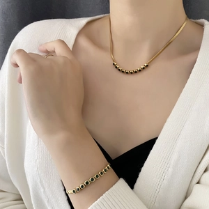 Elegant gold snake chain necklace and bracelet set featuring vibrant green zircon stones
