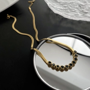 Unique gold snake chain necklace with nine round black zircon stones in a curved layout