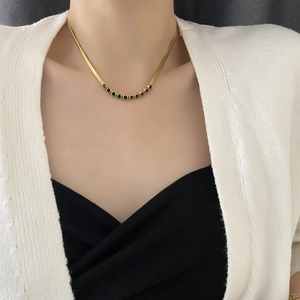 Golden snake chain necklace with nine green zircon gemstones in a vintage French style