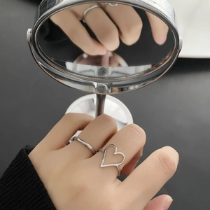 Ensemble de bagues coeur évidé argentées portées à la main avec reflet de miroir