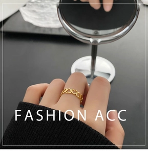 Detail of gold heart-shaped stackable rings worn on hand with minimalist hollow design