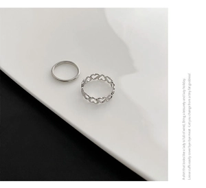 Macro shot of a two-piece silver stainless steel ring set with a heart cutout design