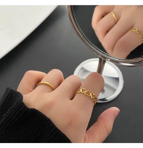 Close-up of gold heart cut-out ring and minimalist band set shown in mirror reflection