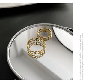 Close-up of dual heart-shaped cutout and minimalist polished golden rings on mirror