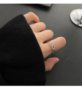 Detail view of heart-shaped hollow rings in silver finish worn on a finger