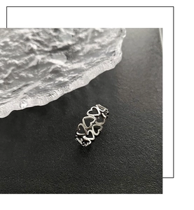 Detail shot of silver hollow heart-shaped titanium steel ring on textured surface