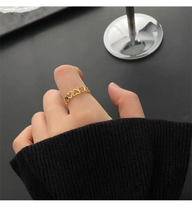 Detailed view of a gold heart cutout ring set in titanium steel on a model's finger