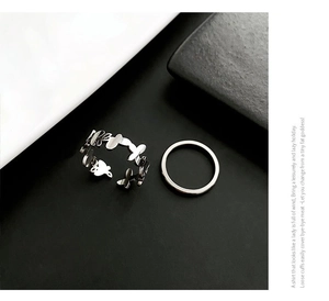 Close-up of minimalist silver butterfly pattern cutout ring and smooth band set