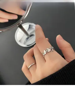 Detailed view of butterfly and leaf wrap ring set in silver finish on a hand