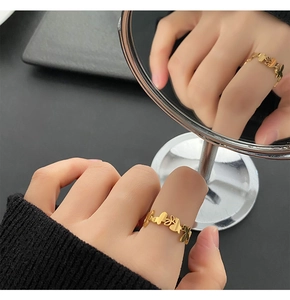 Golden butterfly and heart cut-out ring detail reflected in a circular mirror