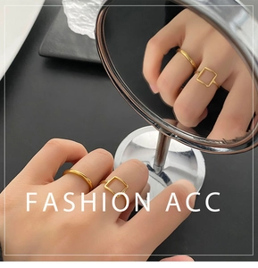 Close-up of minimalist square and slim gold rings shown with mirror reflection