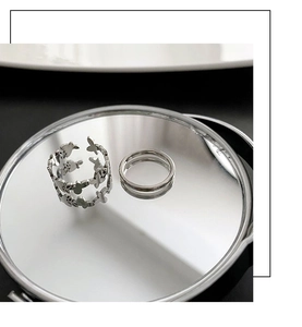 Detailed view of silver butterfly cutout ring set with reflection on mirror surface
