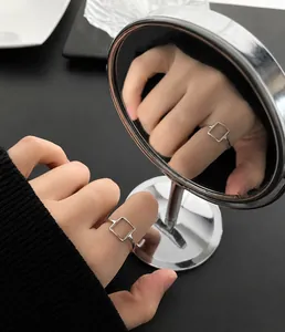 Macro shot of silver square hollow ring with mirror reflection on index finger
