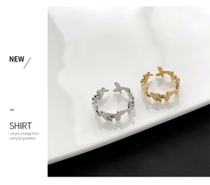 Detailed close-up of butterfly cut-out open rings in gold and silver on ceramic plate