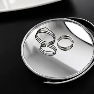 Macro shot of two-piece silver titanium steel geometric rings on a mirror surface